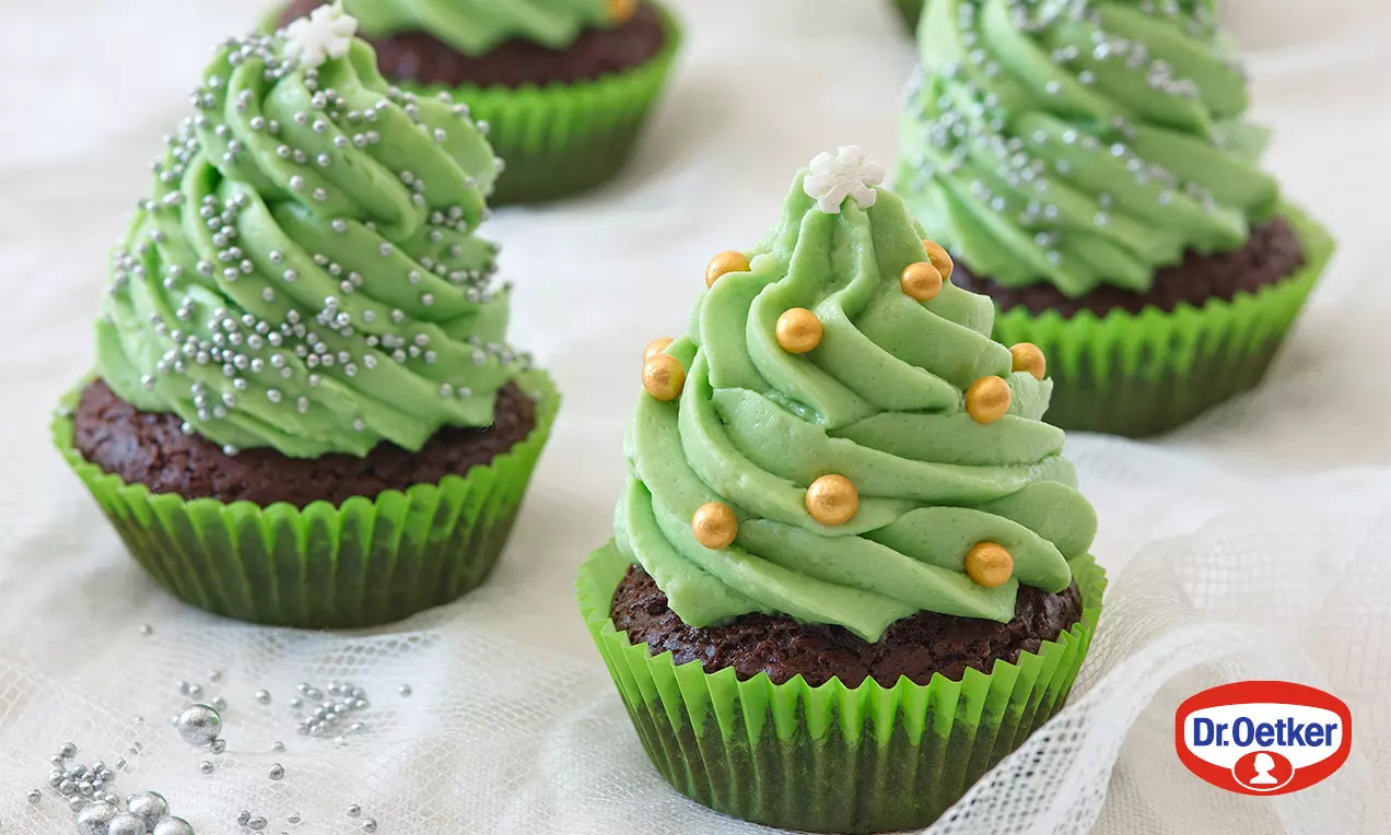 Čokoládové cupcakes v limetkových košíčcích s vrstvou zeleného krému tvarovaného do podoby stromečků, zdobené zlatými kuličkami a hvězdou
