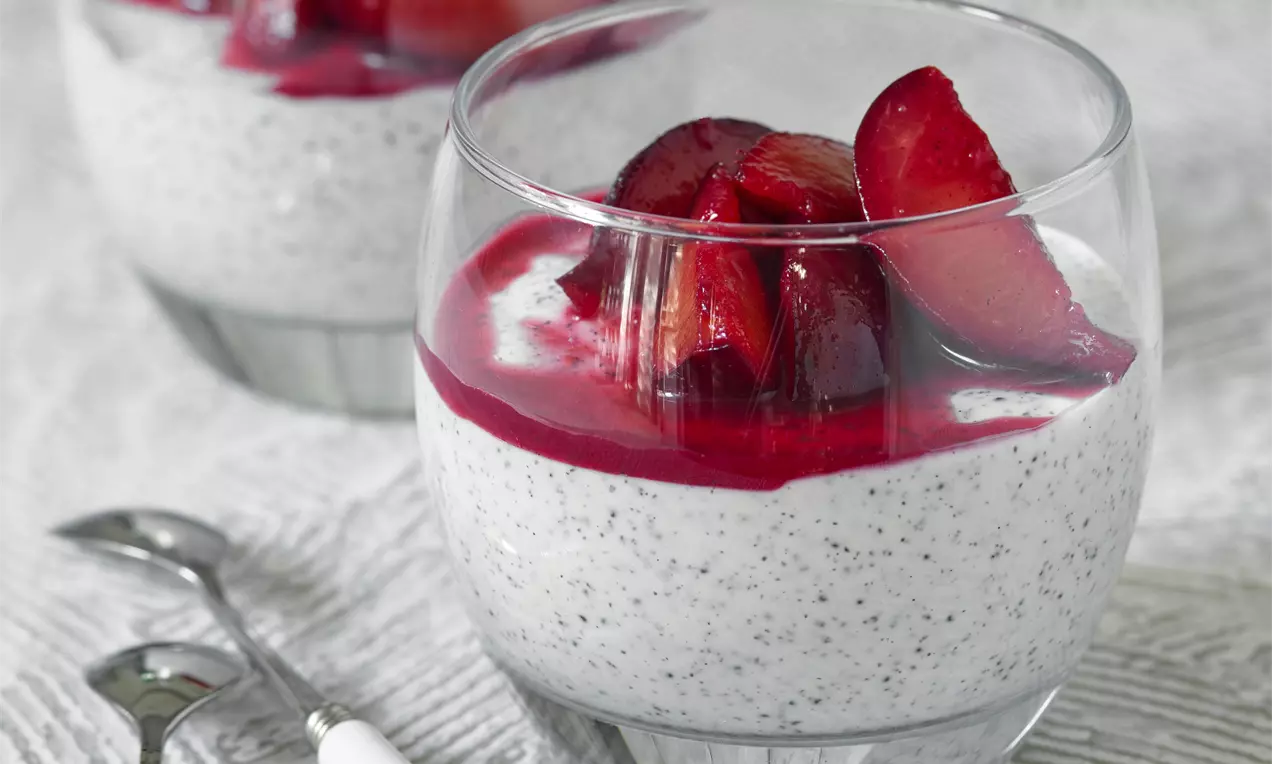 Maková panna cotta se světlým krémem jemně posetým makovými zrníčky, doplněná lesklými červenými švestkami a ovocnou omáčkou ve skleničce