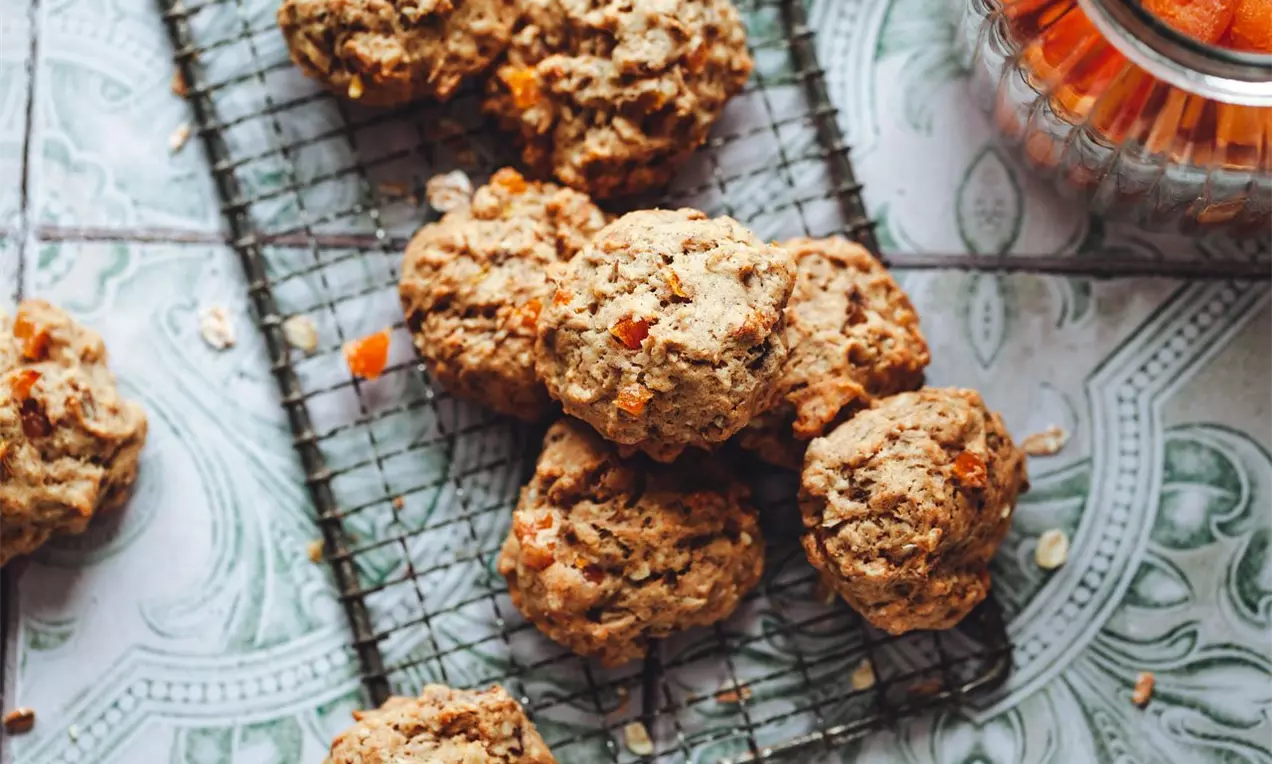sušenky se sušenými meruňkami naaranžované na pekařské mřížce na modrých dlaždicích.