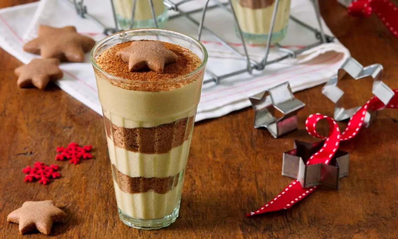 Perníkové tiramisu ve sklenici s vrstvami světlého krému a tmavého perníku, nahoře posypané kakaem a ozdobené perníčkovou hvězdou