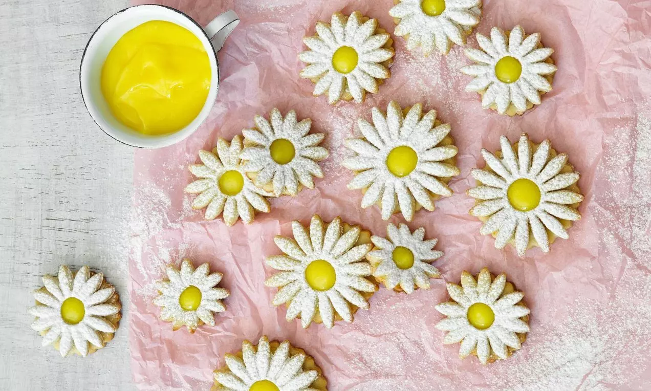 Sušenky ve tvaru kopretin se žlutým citrónovým krémem na růžovém a bílém podkladu