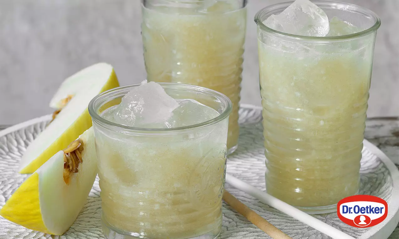 Světle zelené melounové smoothie s krémovou texturou, podávané v průhledných sklenicích s ledovými kostkami na bílém reliéfním talíři